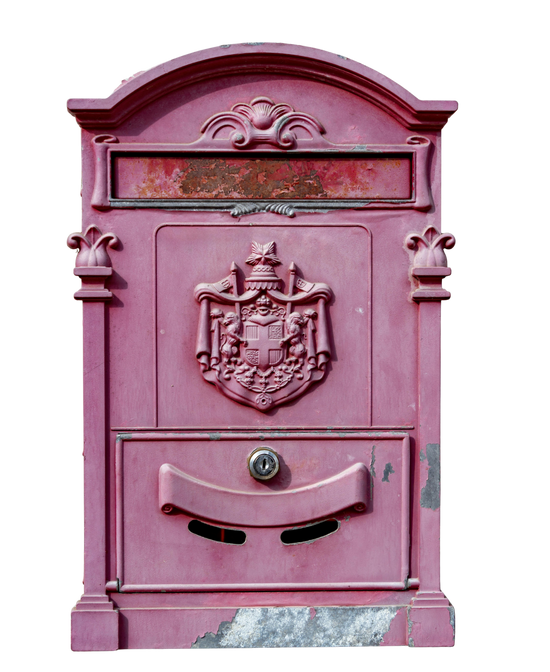 A vintage-style metal mailbox in a dusty rose pink color, featuring an embossed crest on the front, a curved slot drawer, and weathered details, isolated on a white background.